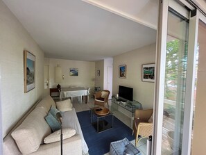 Una sala de estar con un sofá, un televisor, una mesa de comedor y una mesa de centro de vidrio.