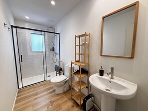 Ein modernes Badezimmer mit Duschkabine aus Glas, Toilette, Holzregal, Waschbecken und Spiegel.