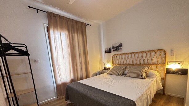 A bedroom with a bed, bedside lamps, a wardrobe, and a window with curtains. - Renovated house near the beach - 8 guests (Roses)