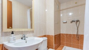 Un baño con lavamanos, inodoro, ducha y espejo.