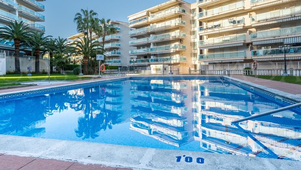 Una piscina con superficie de agua azul cristalina, rodeada de edificios residenciales de varios pisos con balcones.