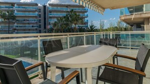 Un balcón con una mesa redonda y sillas, con vistas a una piscina y edificios.