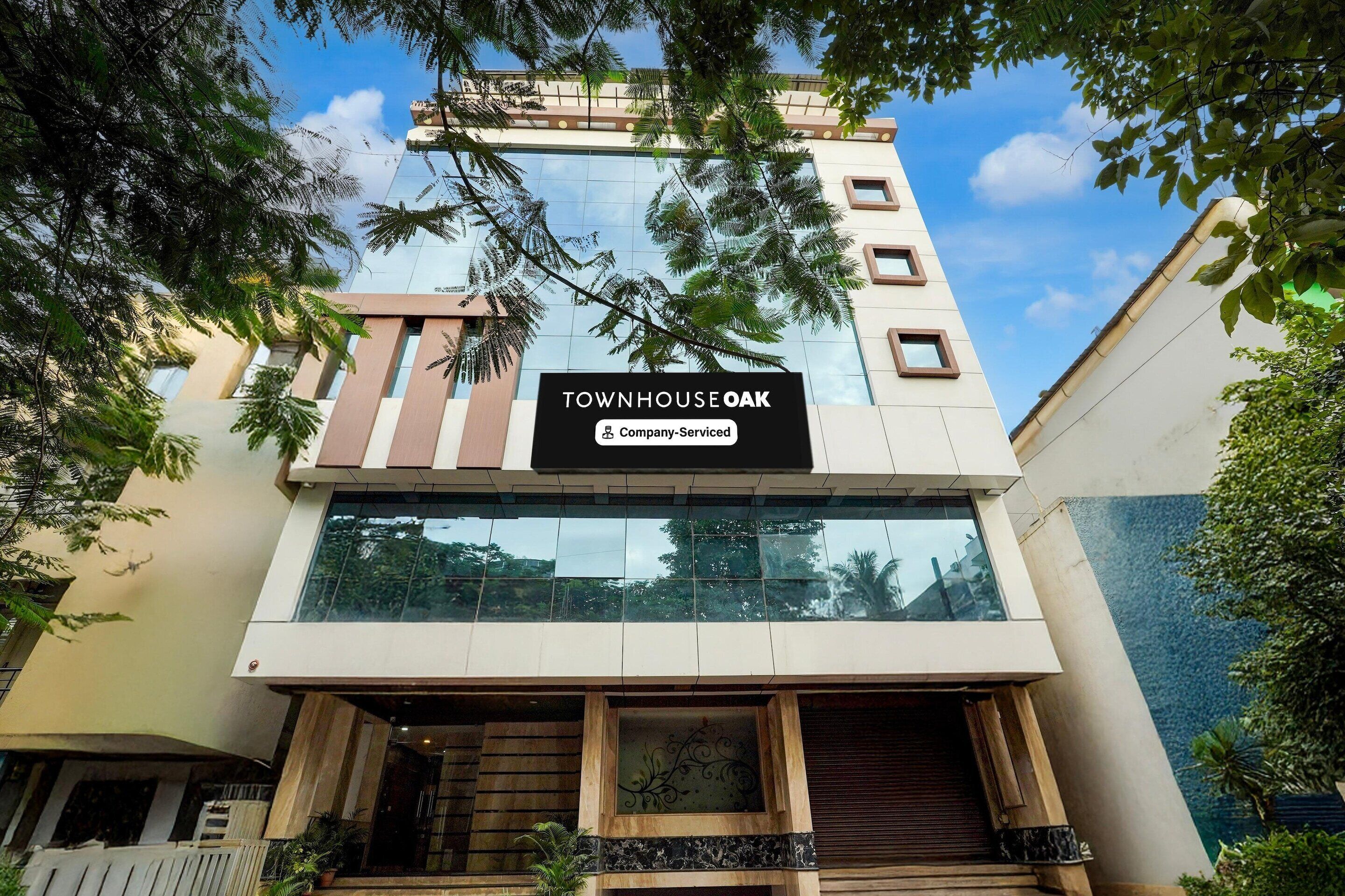 A modern building with a sign reading 'TOWNHOUSE OAK' and a company-serviced label.