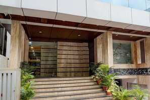 A modern building entrance with a wooden ceiling, stone steps, and potted plants. - Single Room Blue Ocean Residency (Bengaluru)