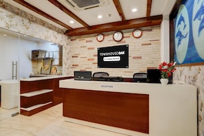 A reception desk with a sign reading 'Townhouse Oak,' a clock, and a mural of dolphins. - Single Room Blue Ocean Residency (Bengaluru)