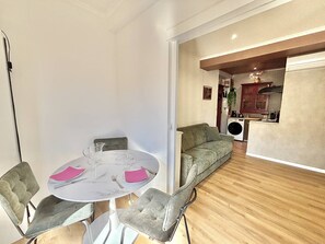 A dining area with a round table, chairs, and a kitchen in the background. - Central studio, AC - 2 guests (Ajaccio)
