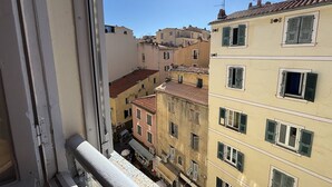 Blick aus einem Fenster auf eine Reihe mehrstöckiger Gebäude mit Balkonen und traditioneller Architektur.