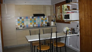 A kitchen with a tiled backsplash, a microwave, and a dining area with chairs. - Cozy chalet - 6 guests (Roche-des-Arnauds)