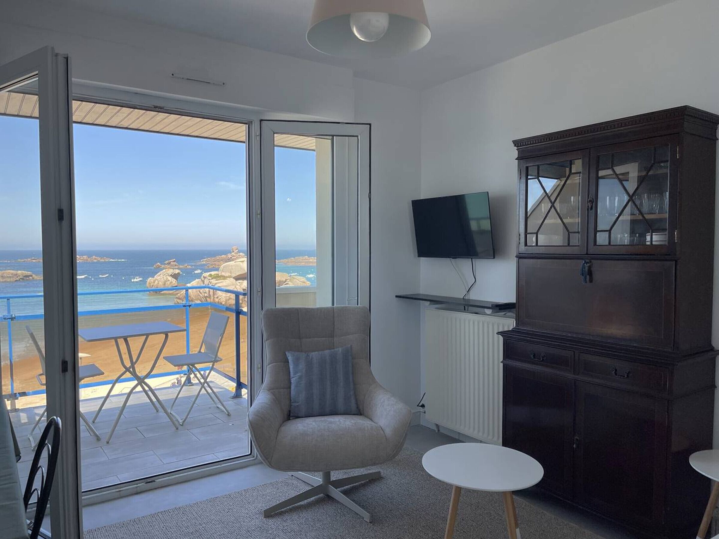 Une chambre avec vue sur l’océan, une chaise, un téléviseur, une armoire et une petite table.