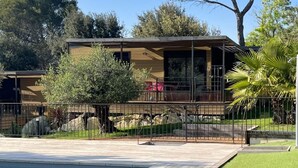 Uma casa moderna com piscina, cercada por uma vedação e vegetação.