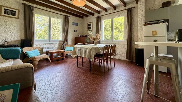 A cozy room with a dining area, a sofa, a table with chairs, and a kitchen area with a counter and appliances. - Comfortable family apartment - 4 guests (Saint-Pierre-d'Oléron)