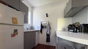 A compact kitchen with a refrigerator, sink, and a microwave. - Comfortable family apartment - 4 guests (Saint-Pierre-d'Oléron)