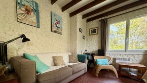 A cozy living room with a sofa, a chair, a table, and artwork on the walls. - Comfortable family apartment - 4 guests (Saint-Pierre-d'Oléron)