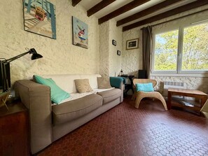 Un salon chaleureux avec un canapé, un fauteuil, une table et des œuvres d’art accrochées aux murs.