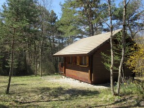 A wooden cabin with a sloped roof, surrounded by trees.