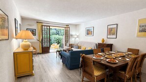 A dining area with a table set for four, a sofa, and a chair. - Spacious apartment, calm and greenery - 7 guests (Saint-Raphaël)