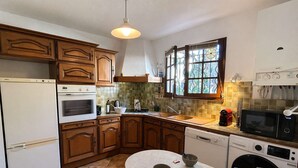 A kitchen with wooden cabinets, a white refrigerator, an oven, a microwave, a dishwasher, and a window with a view. - Spacious apartment, calm and greenery - 7 guests (Saint-Raphaël)