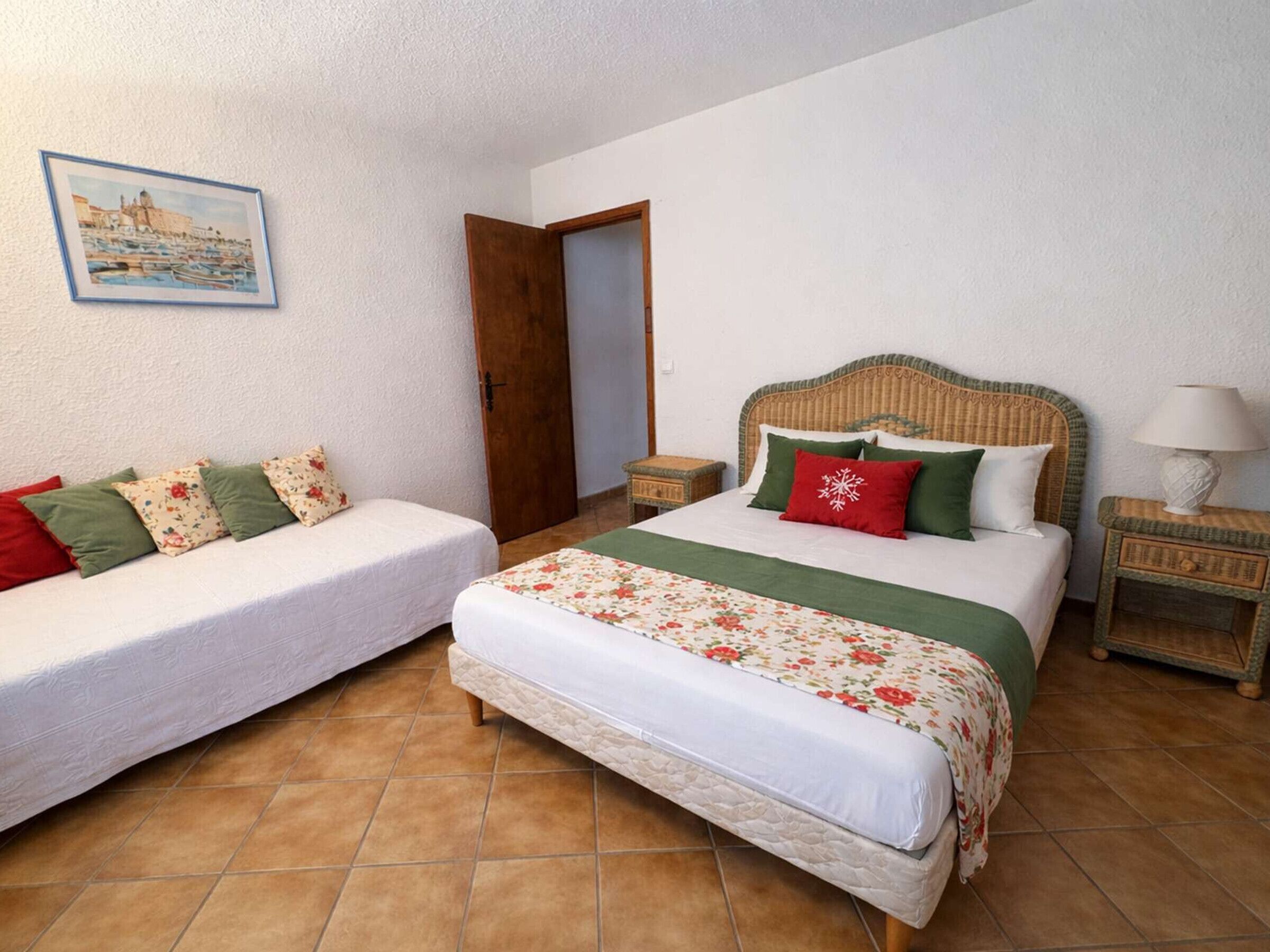 A bedroom with two beds, a nightstand, a lamp, and a framed picture on the wall.
