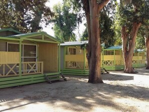 A row of small, green cabins with wooden railings and a dirt ground. - Chalet with AC and pets - 5 guests (Algajola)