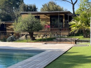 Une maison moderne avec une piscine, entourée d’une clôture et de verdure.