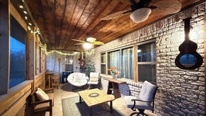 Una camera accogliente con soffitto in legno, pareti in pietra, un'ampia finestra e una ventola a soffitto.