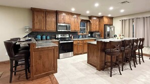 Una cucina moderna con mobili in legno, elettrodomestici in acciaio inossidabile e un'isola centrale con sgabelli da bar.