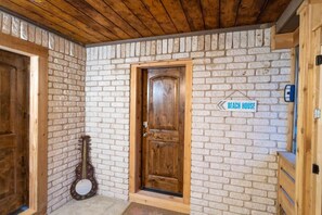 A wooden door with a sign reading 'Beach House' above it, a guitar leaning against the wall, and a wooden bench to the right. - The Whole Zen Lodge: Main House+2 Private Hot Tubs (Lawton)