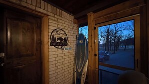 Una porta di legno, un muro in mattoni con un logo e una tavola da surf appoggiata al muro.