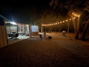 An outdoor area with a covered seating area, string lights, and a grill. - The Whole Zen Lodge: Main House+2 Private Hot Tubs (Lawton)