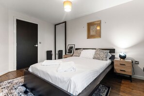 Ein Schlafzimmer mit einem Bett, Nachttischen, einer Wandlampe und einer Tür.