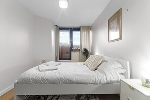 Ein Schlafzimmer mit Bett, Nachttisch und Blick ins Freie.
