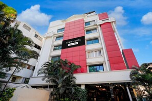 Un edificio de varios pisos con una fachada destacada en rojo y blanco, un letrero que dice 'TOWNHOUSE' y un cielo azul despejado al fondo.