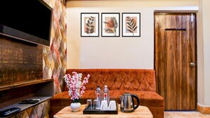 Una sala de estar con un televisor de pantalla plana, un sofá, una mesita de centro con una bandeja de objetos y obras de arte enmarcadas en la pared.