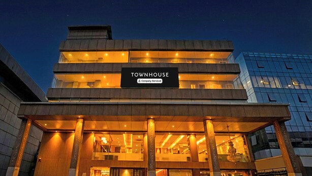 Een meerlaags gebouw met een bord waarop 'TOWNHOUSE Company-Serviced' staat.