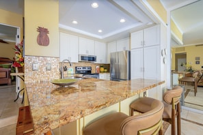 A modern kitchen with white cabinets, stainless steel appliances, and a granite countertop. - 🌊🏄🏻🏝️ Summer in Maui - Kapalua Sunset, Golf and Beach Retreat (Lahaina)