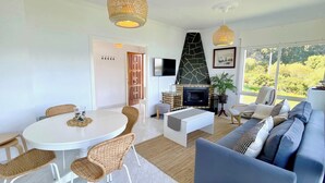 A modern living room with a fireplace, a dining area, and a sofa.
