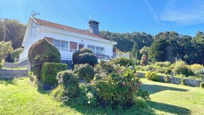 Una casa de dos pisos con fachada blanca, techo de tejas rojas y un balcón.