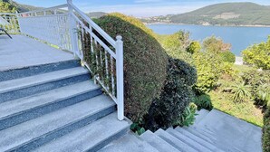 A staircase with a white railing leading to a scenic overlook with a lake and hills in the background.