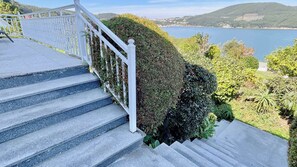 Una escalera con barandilla blanca que lleva a un mirador panorámico, con un lago y colinas al fondo.