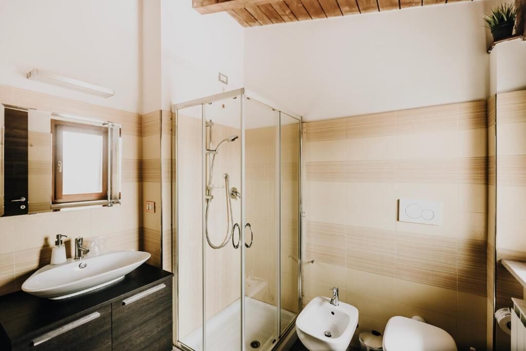 A modern bathroom with a glass-enclosed shower, a sink, and a bidet.