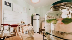 Una cocina con refrigerador, dispensador de agua y una mesa con jarra y vaso.