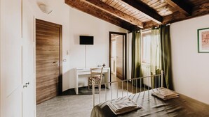 Un dormitorio con techo de madera, un escritorio, una silla, una cama y una ventana con cortinas.