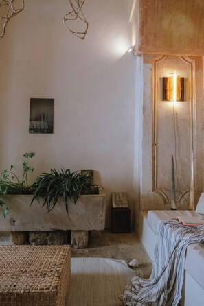 Ein gemütliches Zimmer mit einer Couch, einem kleinen Tisch, einer Stehlampe und einer Wandleuchte.