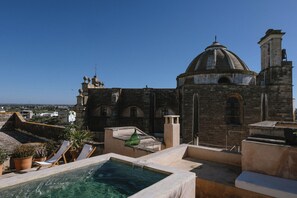 Ein Pool auf dem Dach mit Blick auf ein historisches Gebäude mit Kuppel und Rundbogenfenstern.