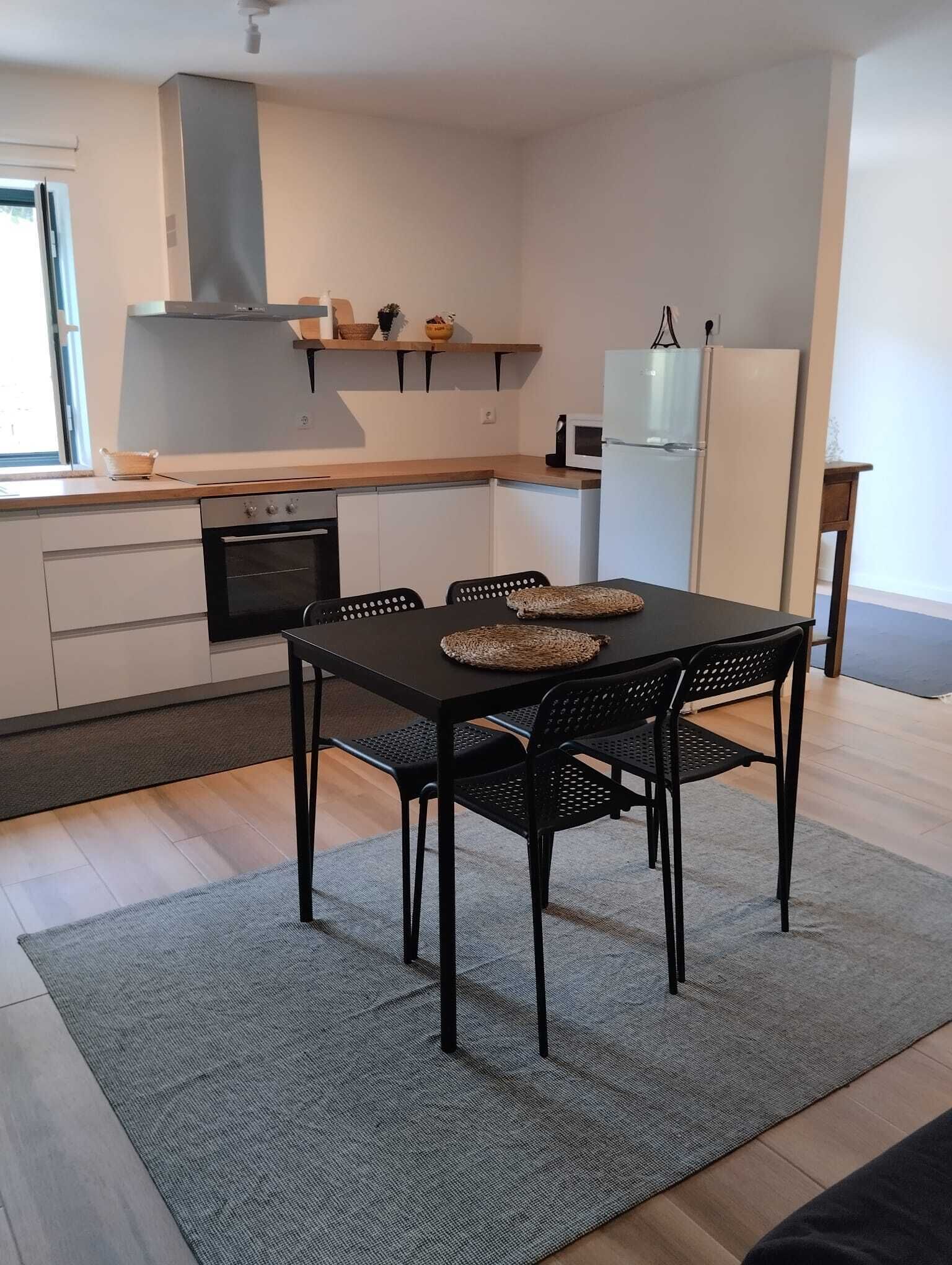 Uma cozinha moderna com uma mesa de jantar, cadeiras e uma geladeira.