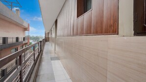 Un pasillo con suelo de baldosas, pared de madera y barandilla de metal.