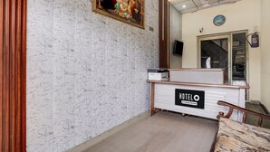 Una recepción de hotel con una pared de mármol y un cuadro religioso enmarcado.