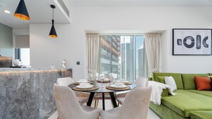 Ein modernes Wohnzimmer mit Essbereich, einem grünen Sofa und einem großen Fenster mit Vorhängen.