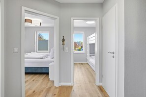 A hallway with a bed, a window, and a door. - Carina vacation apartment in Norddeich with balcony and WLAN for up to 4 people (Norddeich)