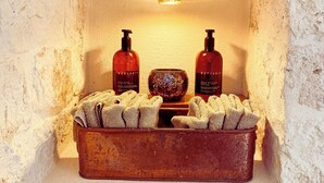 A rustic stone wall with a shelf containing two bottles and a mosaic bowl. - Luxury private condo for 2 w/pool in Apulian hills. Only 15 mins from beach! (Puglia)